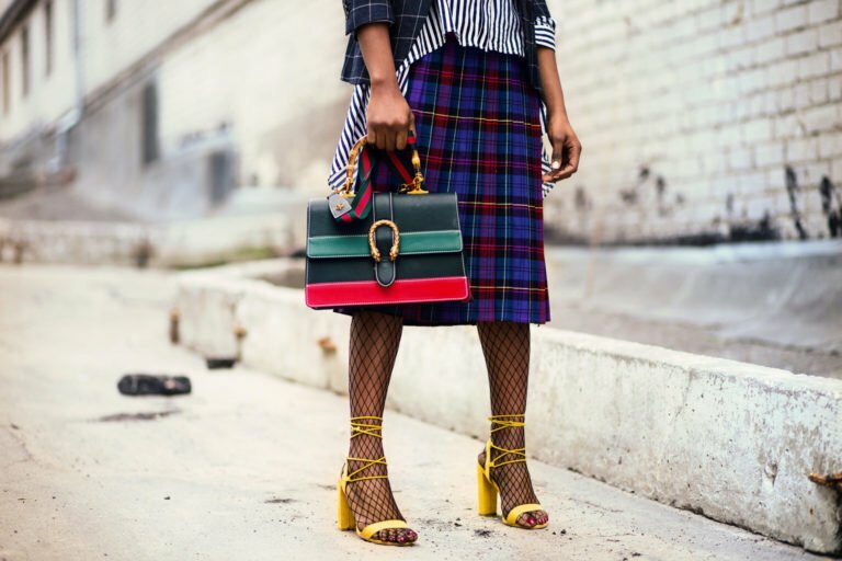 a person holding a purse walking down a sidewalk