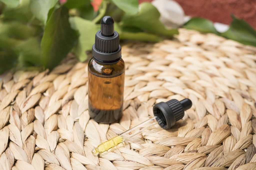 two bottles of brown liquid on a pile of leaves