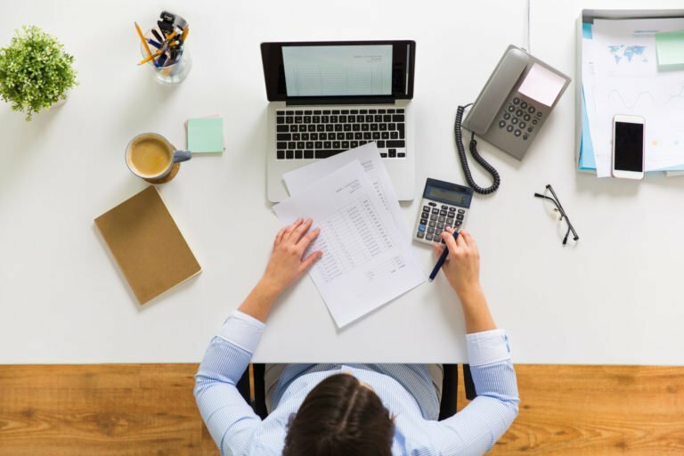 a person sitting at a desk with a computer and papers on it