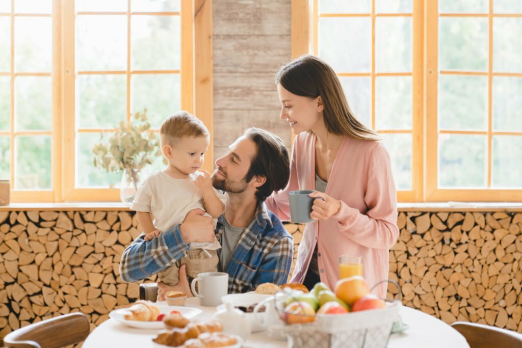 a woman and a couple of kids sitting at a table with food