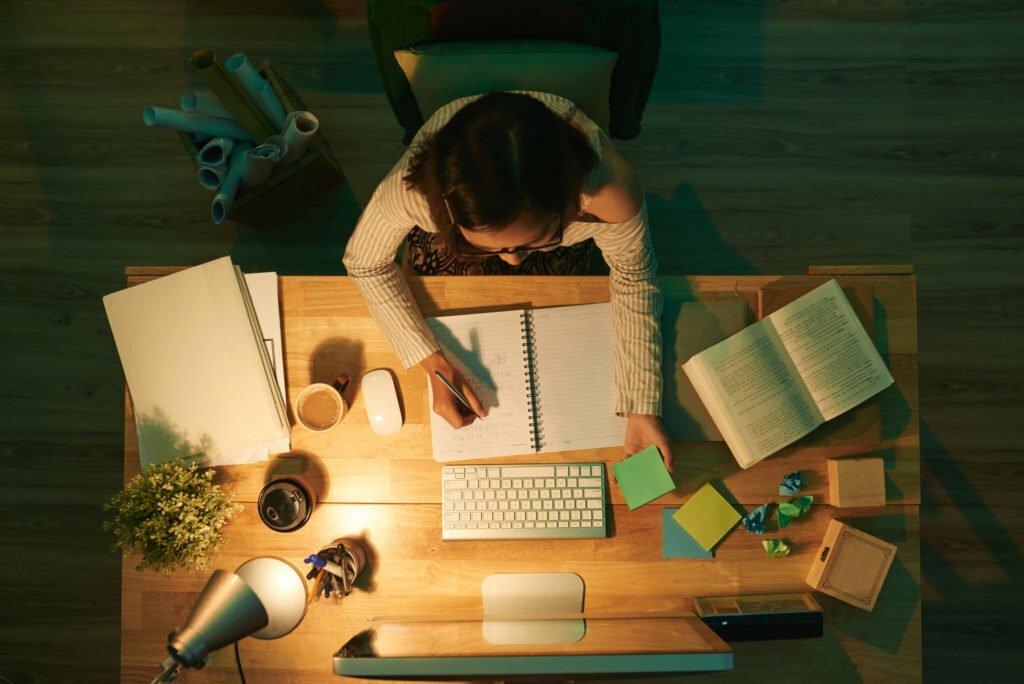 a person sitting at a desk with a computer and papers on it