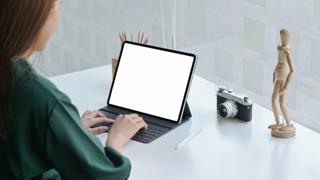 A female traveler with a camera is using a laptop to find travel information.